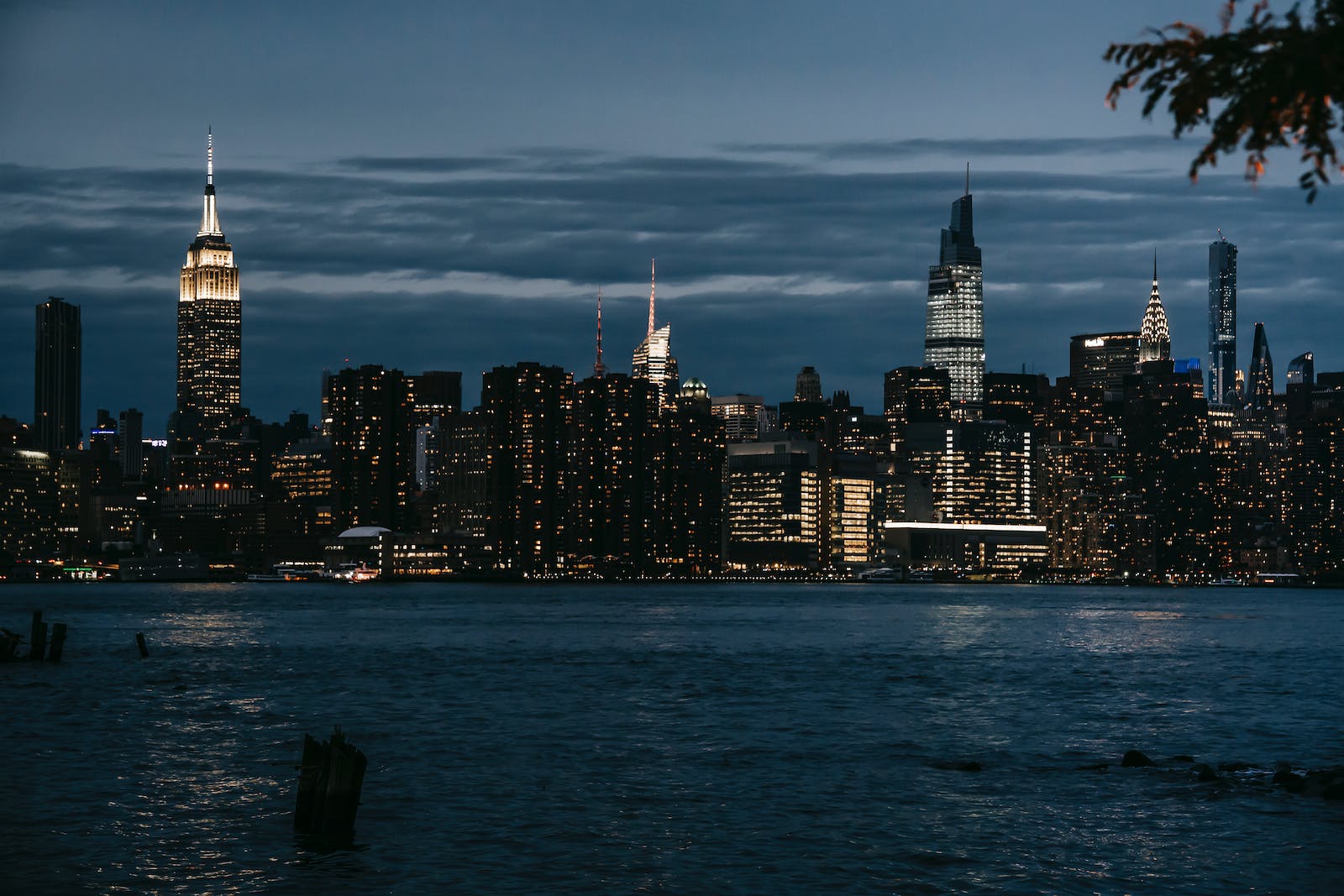 Contemporary illuminated towers located in central district on coast of rippling river in New York at night