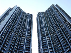 From below of similar contemporary high rise residential buildings with balconies under blue sky